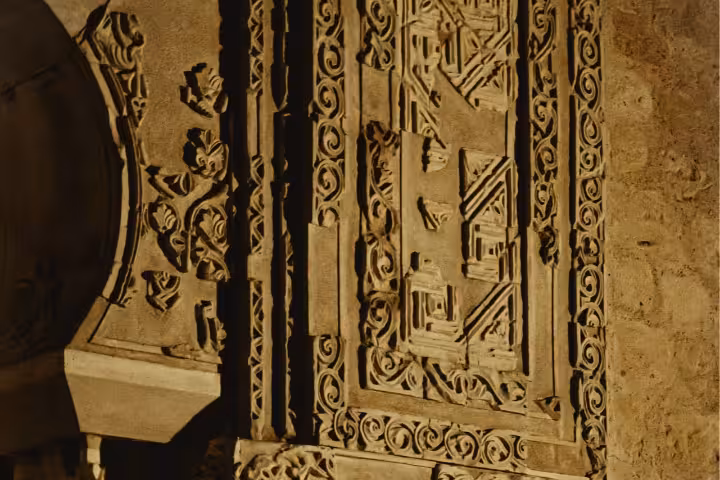 Intricate stone carvings illuminated at night in the historic Medina Azahara, showcasing detailed Islamic artistry.