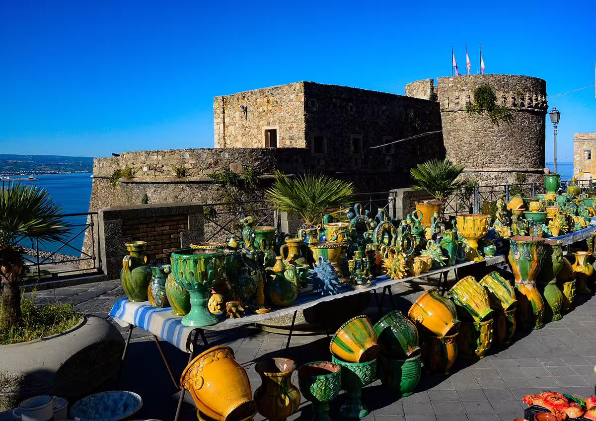 Colorful handmade ceramics displayed by a seaside castle in southern Italy on the Mediterranean Passion driving itinerary