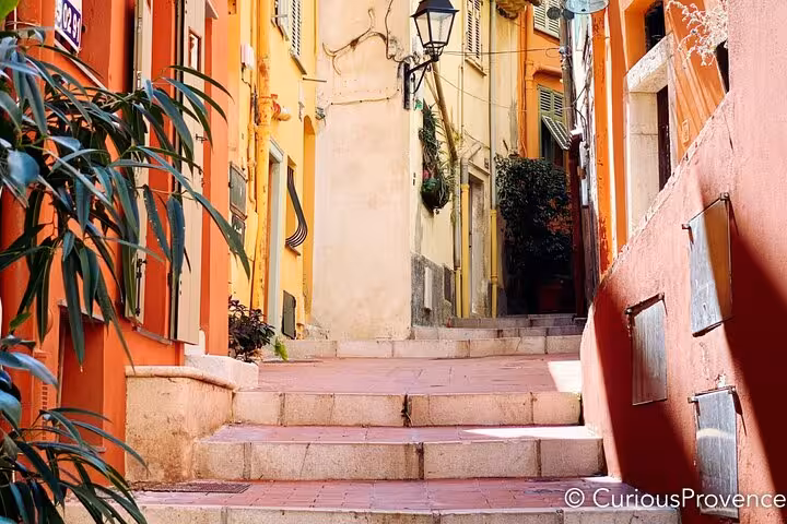 Charming narrow alley in a Mediterranean village with colorful walls and quaint steps, perfect for Riviera exploration.