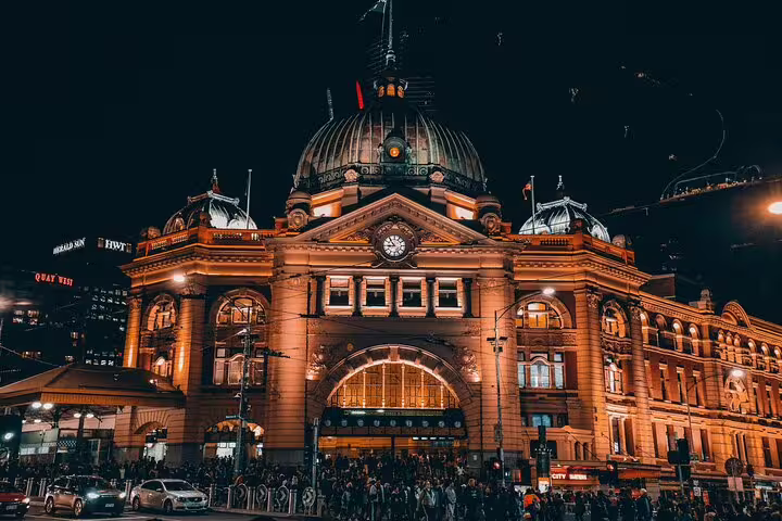 Flinders Street Station illuminated at night with golden lights and crowds below in Melbourne