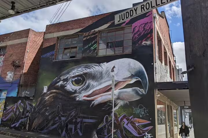 Large eagle street art mural on brick building in Melbourne laneway near Juddy Roller sign