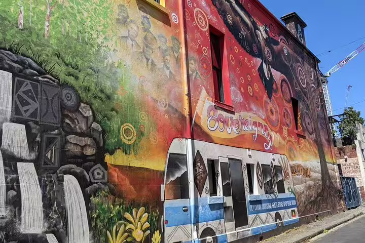 Colorful Aboriginal-themed street art mural covering a building exterior in Melbourne with Sovereignty text