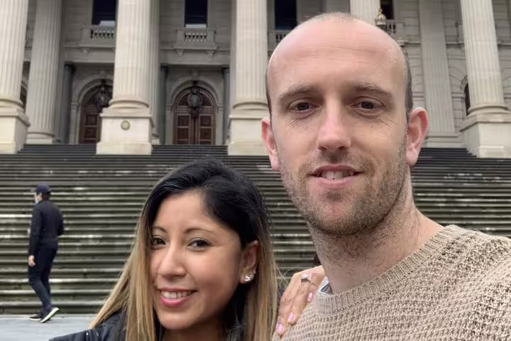 Couple smiling in front of grand historic Melbourne building with tall columns and steps