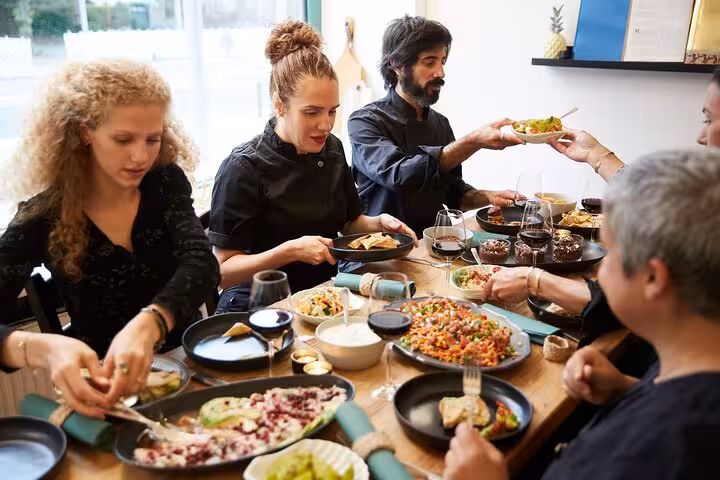 Group of people enjoying a diverse spread of Argentinian cuisine paired with wine at a communal dining table.
