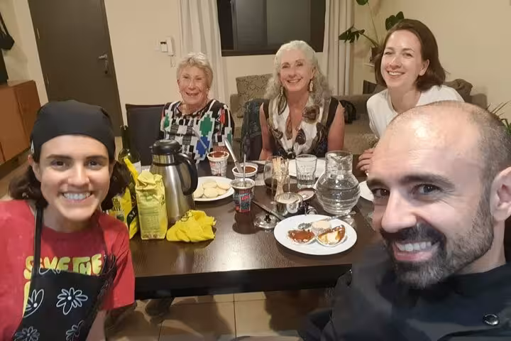 A group of smiling participants gather around a table enjoying traditional Argentinian cuisine and drinks.