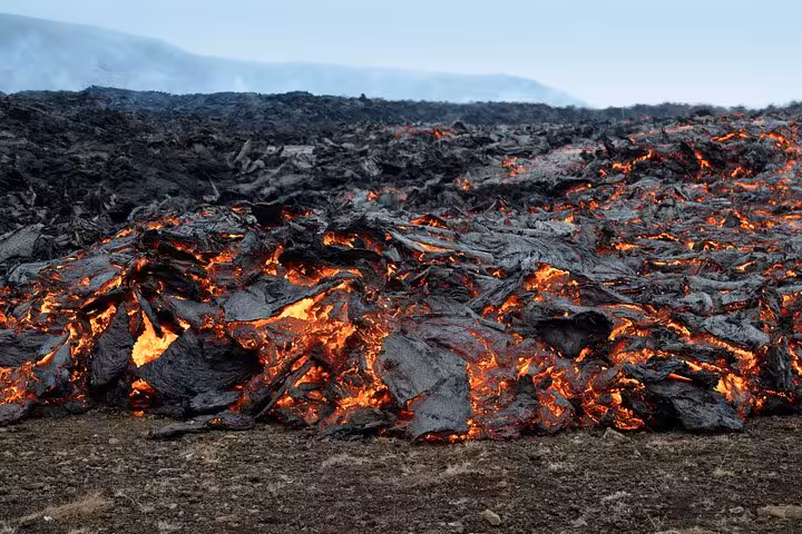 Active lava flow with glowing orange magma spreading across dark volcanic rock in Meradalir Iceland