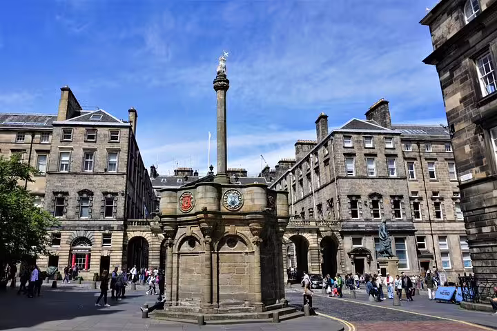 Mercat Cross monument in Edinburgh's Royal Mile with historic stone buildings and tourists