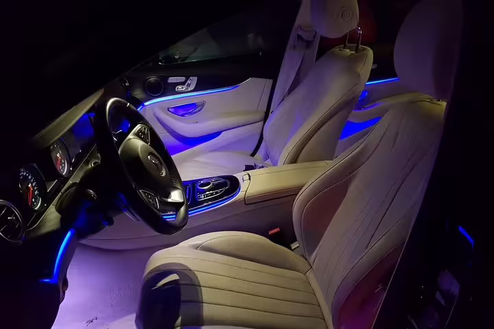 Luxury Mercedes interior with blue ambient lighting and cream leather seats for private airport transfer