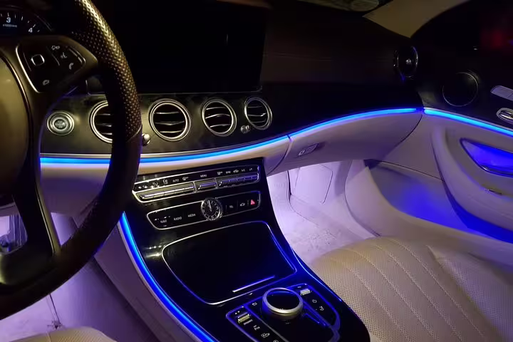 Luxury Mercedes car interior with blue ambient lighting and cream leather seats for private transfer