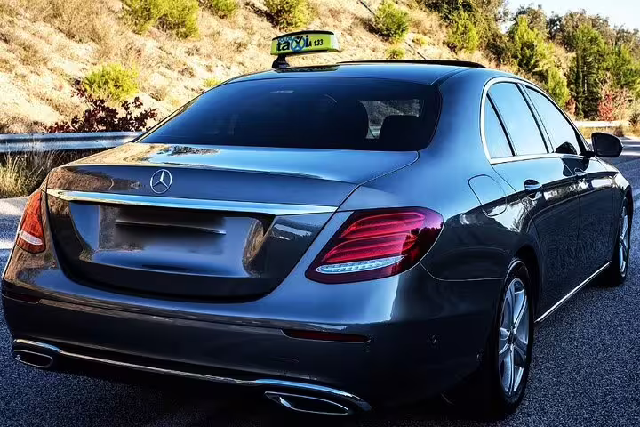 Black Mercedes-Benz luxury taxi sedan rear view on scenic road