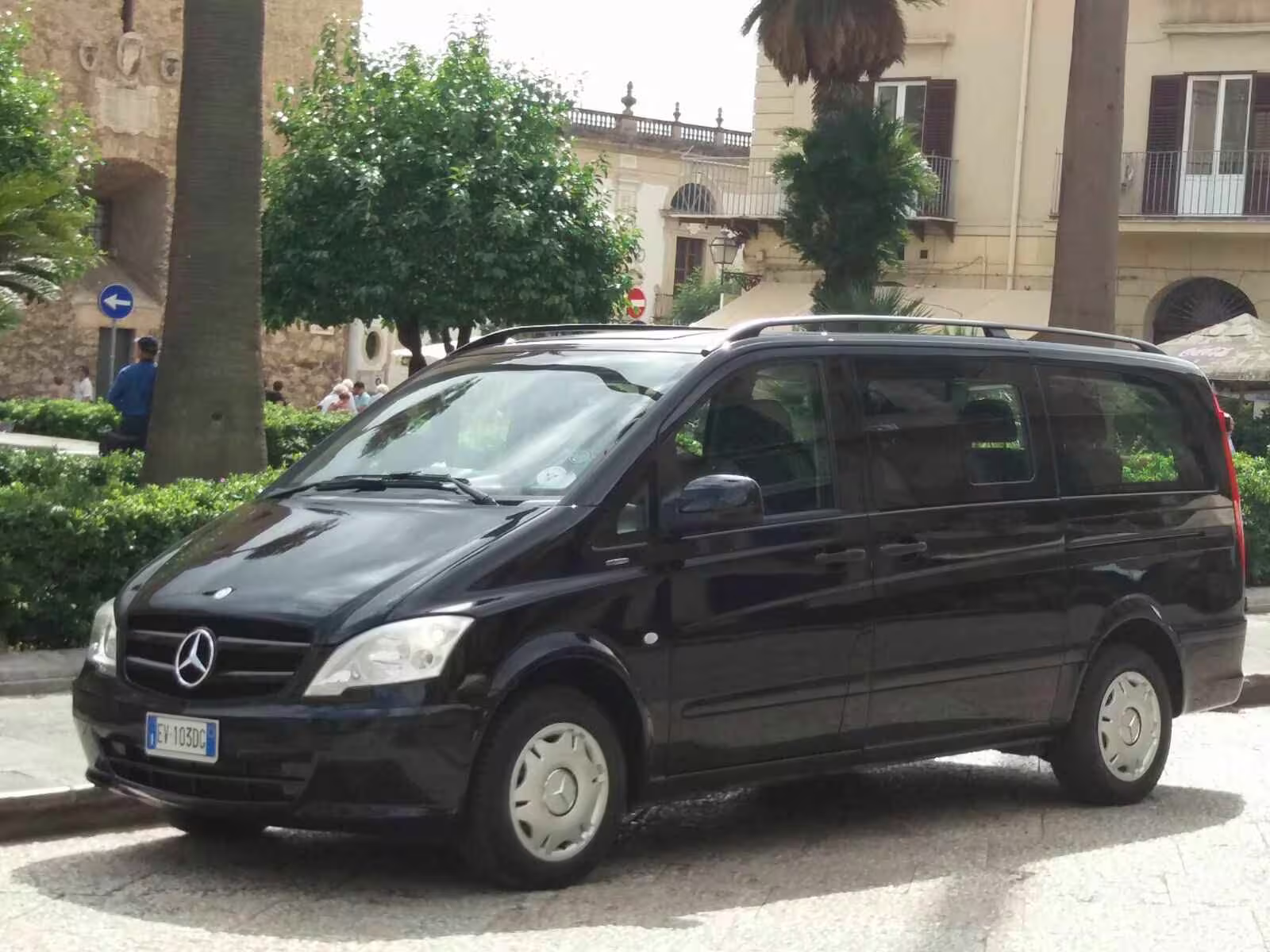 Black Mercedes minivan for private transfer between Naples and Benevento parked in a sunny Italian piazza