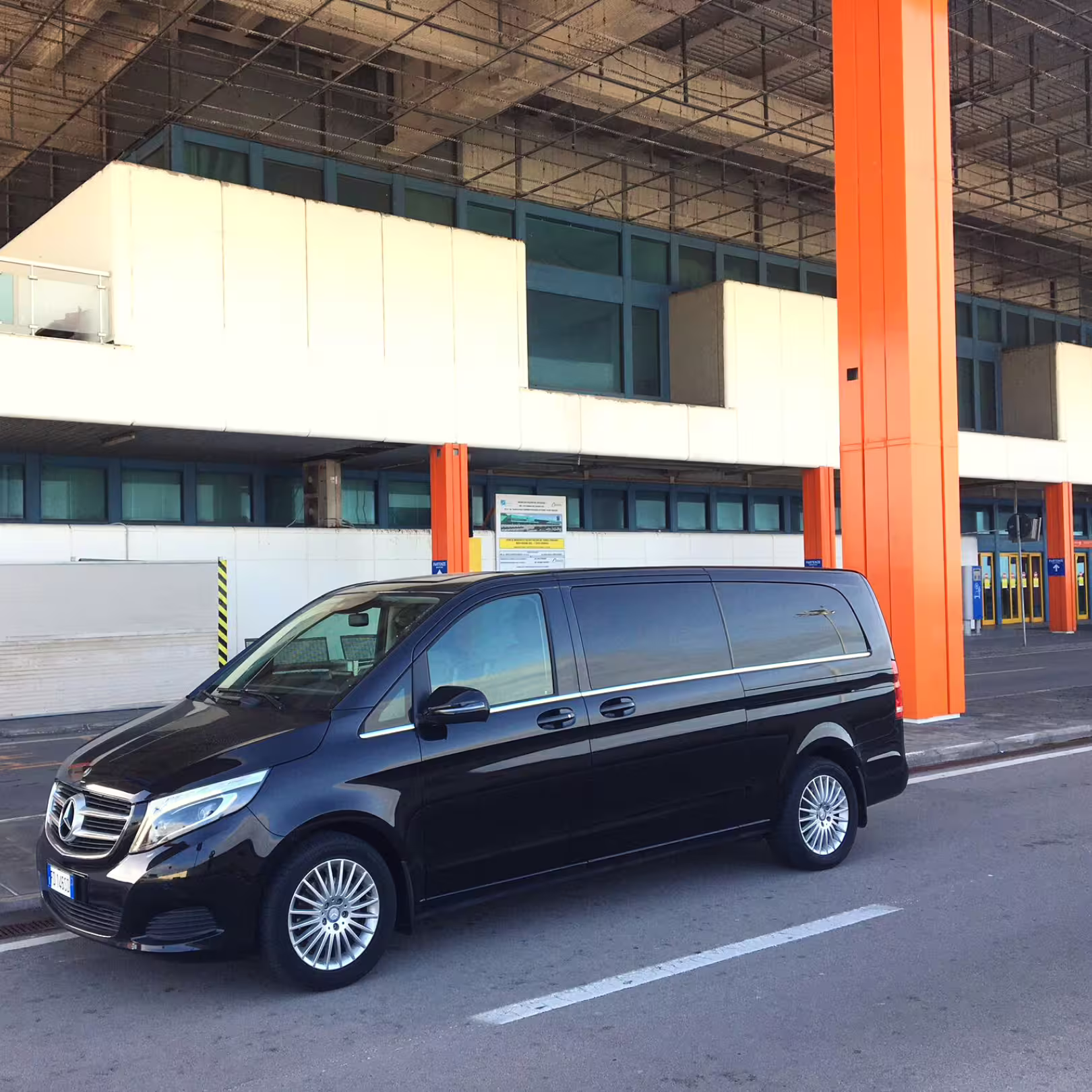 Black Mercedes minivan parked outside Palermo Airport, ready for private transfer service to Hotel Porta Felice hotel