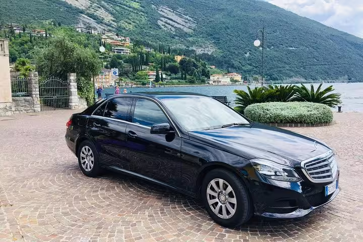 Luxury black Mercedes sedan parked by scenic lakeside for private transfer from Karlsruhe Airport to Baden-Baden