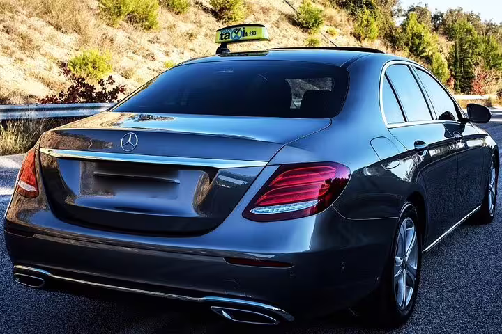 Black Mercedes-Benz sedan taxi for private transfer service on scenic road