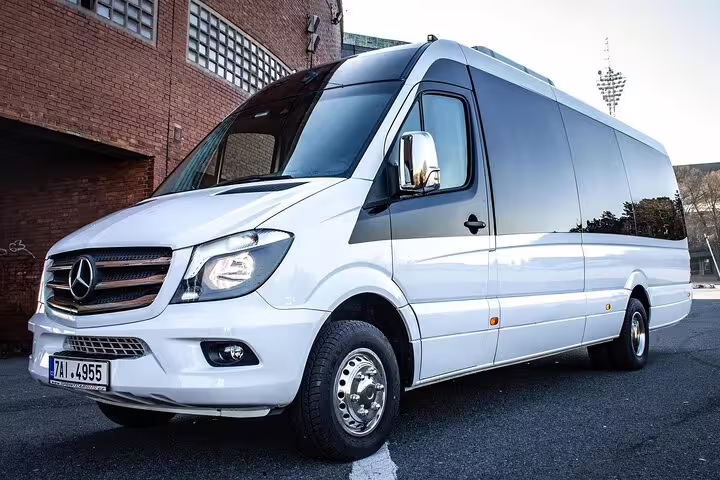 White Mercedes-Benz Sprinter luxury passenger van parked near brick building