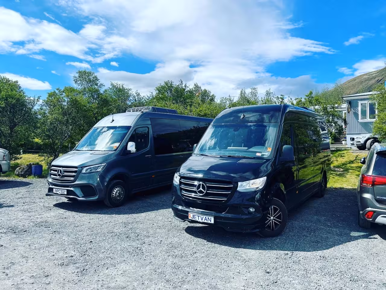 Two black Mercedes-Benz Sprinter vans parked on gravel for Iceland South Coast private tours