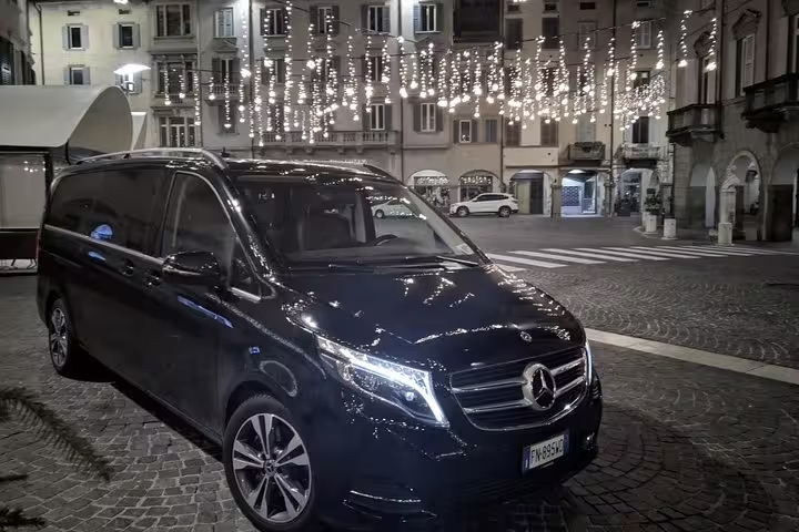 Sleek black Mercedes V-Class minivan parked in city square for premium private transfer to Malaga Airport AGP