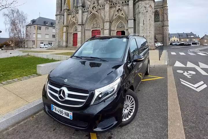 Black Mercedes-Benz V-Class minivan parked in front of a Gothic cathedral in France