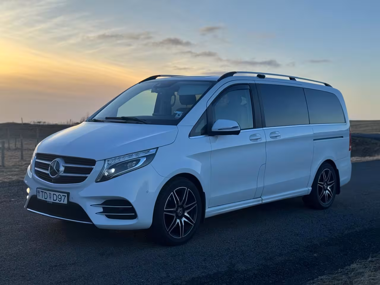 White Mercedes-Benz V-Class luxury minivan parked at sunset in Iceland for private transfer service