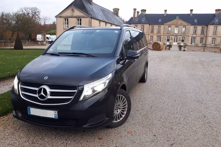 Black Mercedes-Benz V-Class minivan parked in front of a French château for Versailles private transfer