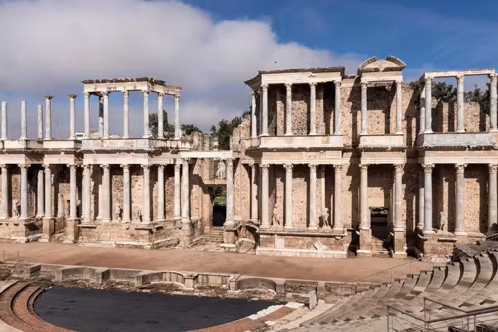 Roman Theatre of Merida with ancient columns and stone stage wall under blue sky, Spain