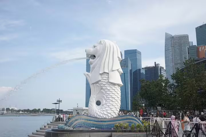 Merlion statue spouting water at Singapore's Marina Bay waterfront with city skyline in background