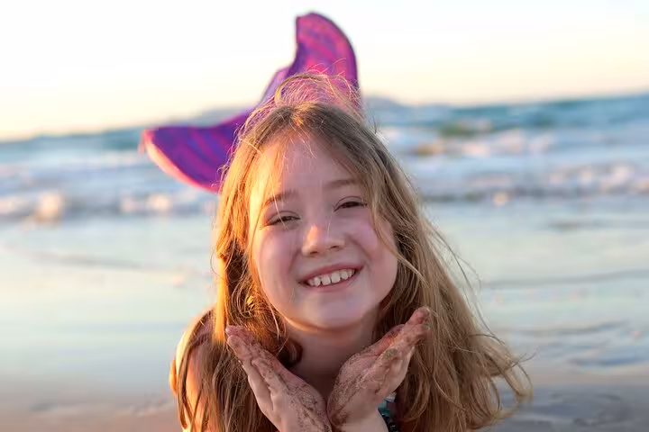 Happy girl with mermaid tail posing on the beach during sunset in Hersonissos photoshoot.