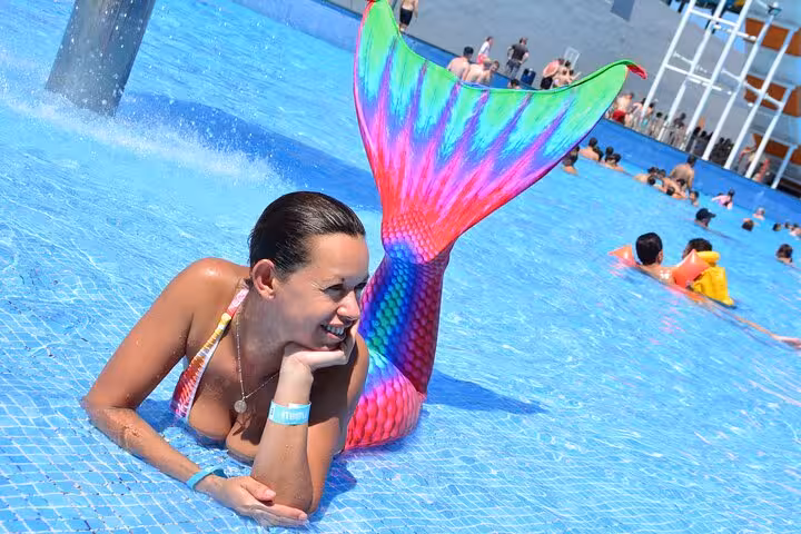 Woman in colorful mermaid tail enjoys a private photoshoot in Hersonissos pool, perfect for memorable vacation moments.