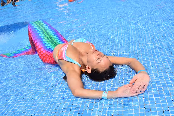 Colorful mermaid tail glistens as a person enjoys a private photoshoot in a sunlit pool in Hersonissos.