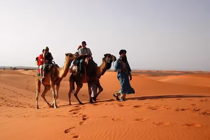 Travelers enjoy a camel ride through the stunning dunes of the Merzouga Desert on a 3-day tour from Fes.