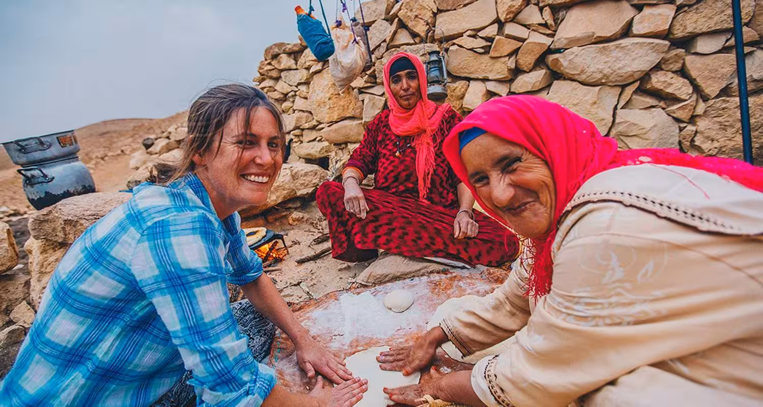 Tourists engaging in traditional bread-making with locals, highlighting cultural experiences on the Merzouga desert safari.