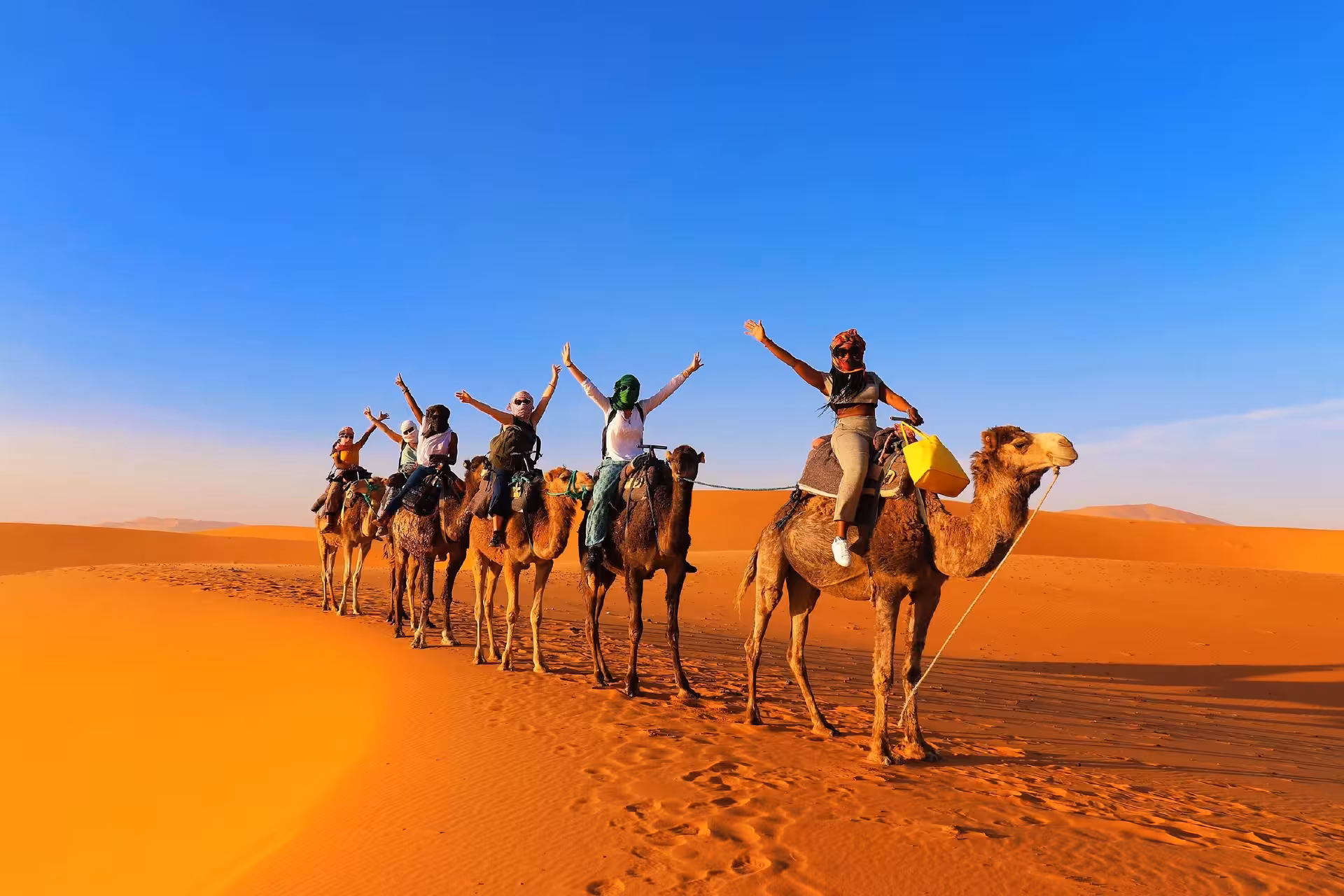 Tourists enjoy camel ride across stunning Merzouga Sahara dunes on 2-day Marrakech to Fez desert adventure.