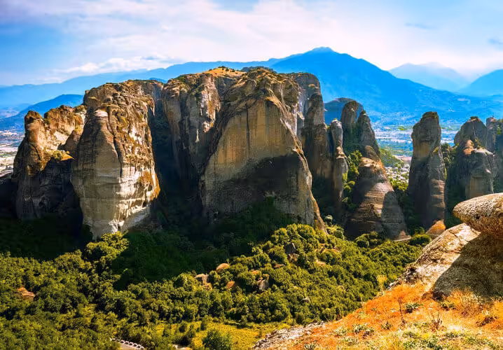 Sunlit Meteora sandstone cliffs above green forest, scenic stop on a 2-day Delphi & Meteora guided tour