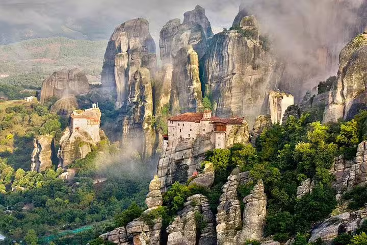 Meteora monasteries and towering cliffs in mist, scenic start for private transfer from Kalabaka to Athens