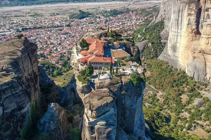 Aerial view of Meteora monastery perched on rock pillar with Kalabaka town below on full day tour