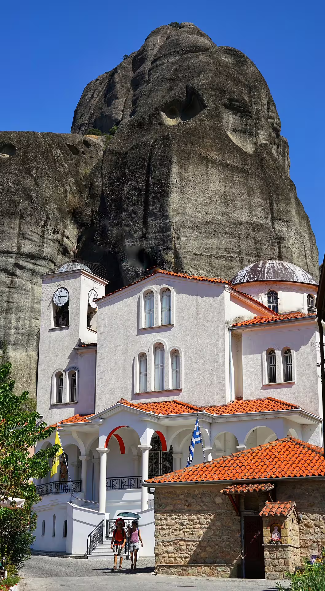 Meteora monastery with red-tiled roofs beneath towering rocks, part of a 2-day private tour from Athens