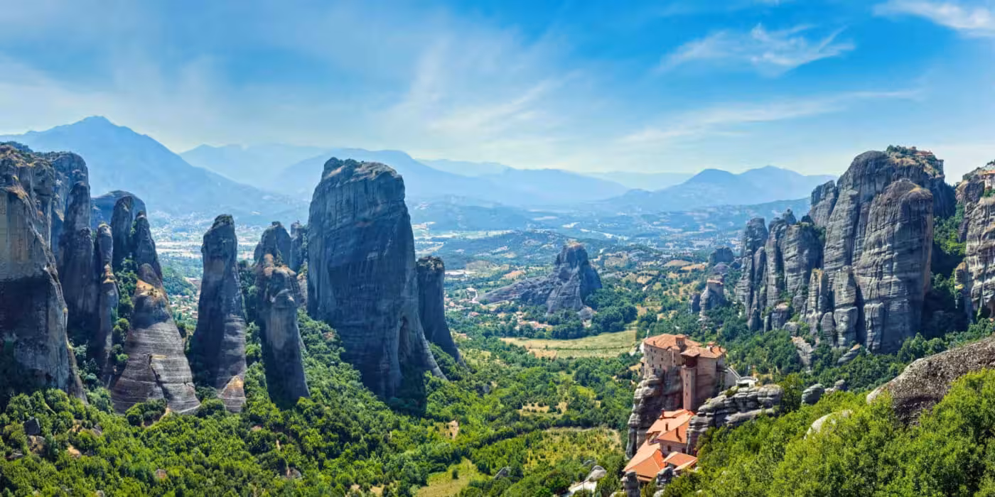 Panoramic view of Meteora rock pillars and cliffside monastery in Greece, featured on the 4-day tour