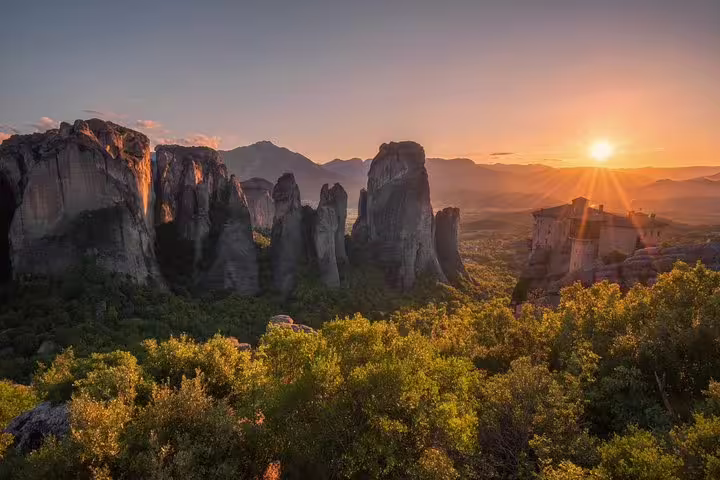 Sunset over Meteora rock pillars and cliffside monastery on a 2-day private tour from Athens via Delphi