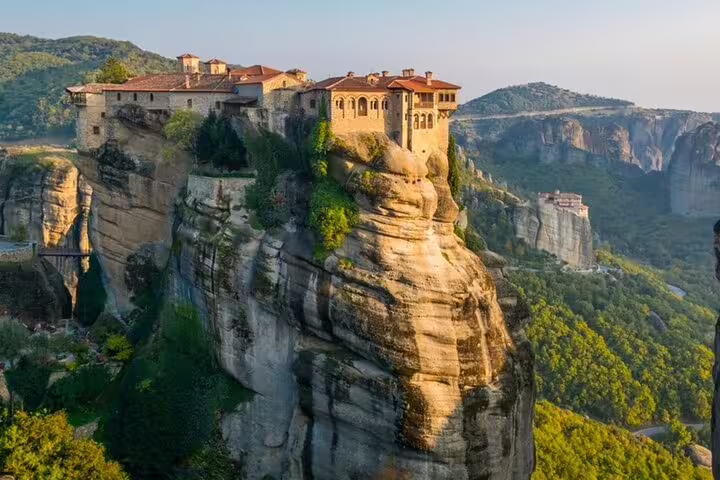 Sunset view of Meteora monastery perched on towering cliffs, highlight of a private day tour from Athens