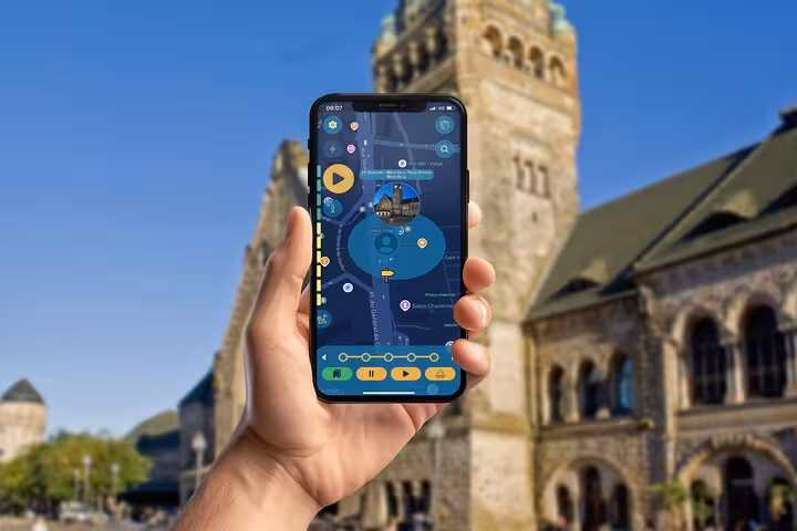Hand holding smartphone with Metz self-guided walking tour app in front of historic stone building