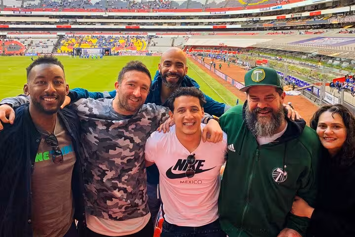 Friends pose in a Mexico City stadium stands on soccer matchday, part of a local fan experience tour