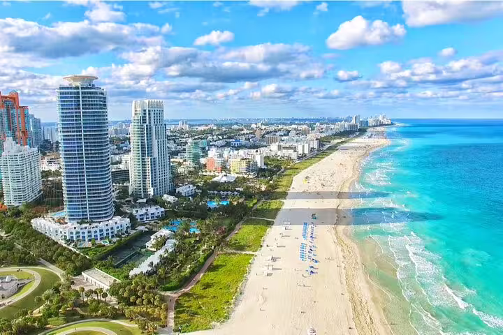 Aerial view of Miami Beach coastline with turquoise water, sandy beach, and Art Deco district buildings