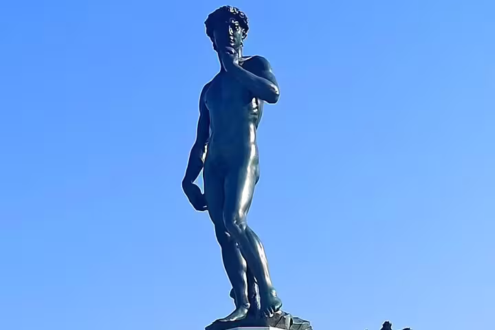 Bronze replica of Michelangelo’s David against a clear blue sky, a highlight of private Florence shore excursions from Livorno