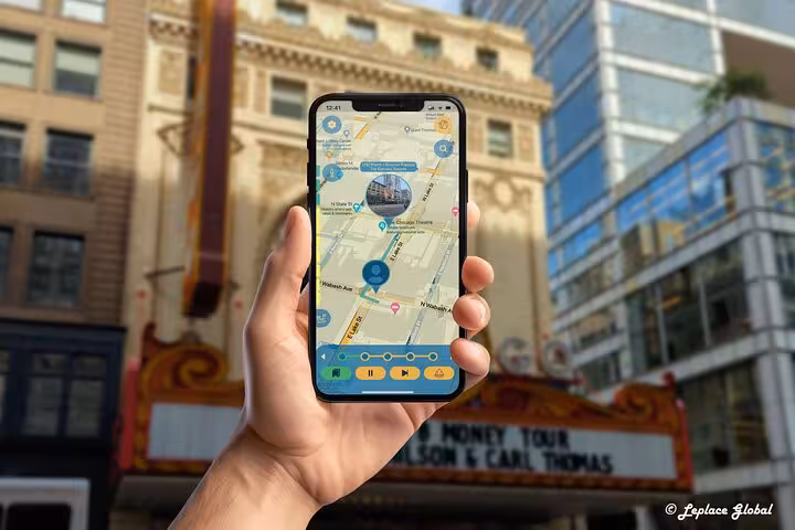 Hand holding smartphone with Chicago walking tour map app on Michigan Avenue with historic theater backdrop