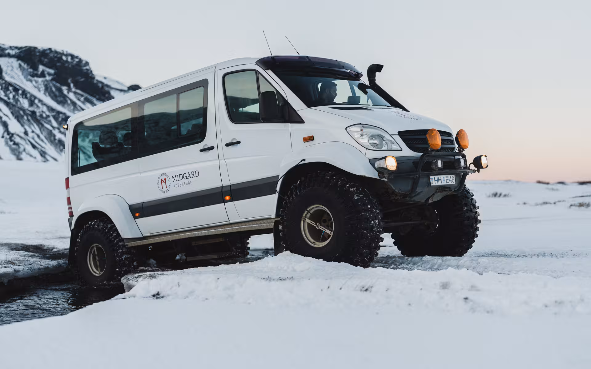 Midgard Adventure super jeep with oversized tires driving through snow near Thorsmork, Iceland