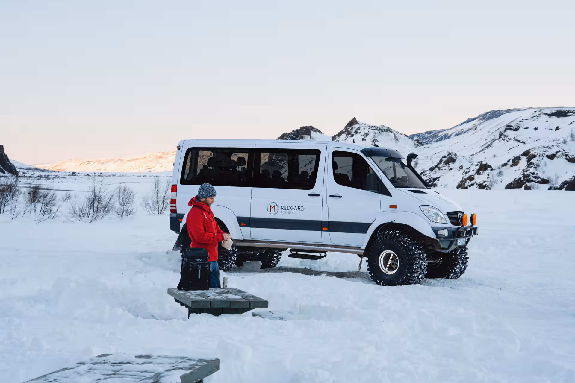 Midgard Adventure super jeep 4x4 van parked in snowy Thorsmork landscape with guide in red jacket