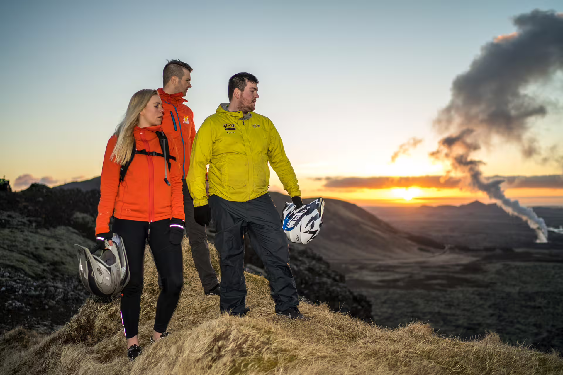 Three adventurers holding ATV helmets at sunset on Reykjanes lava fields Iceland