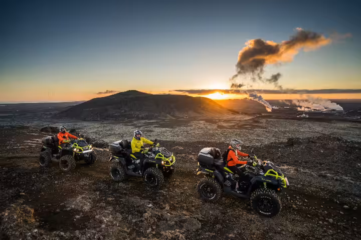 Three ATV riders on quad bikes at sunset over volcanic lava fields in Reykjanes Iceland
