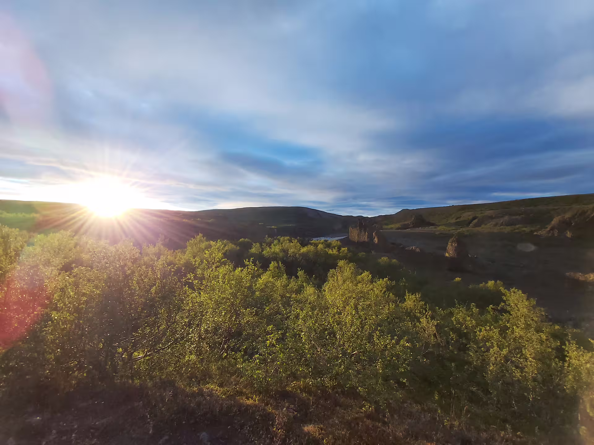 Midnight sun over green shrubs and volcanic landscape in North Iceland Diamond Circle