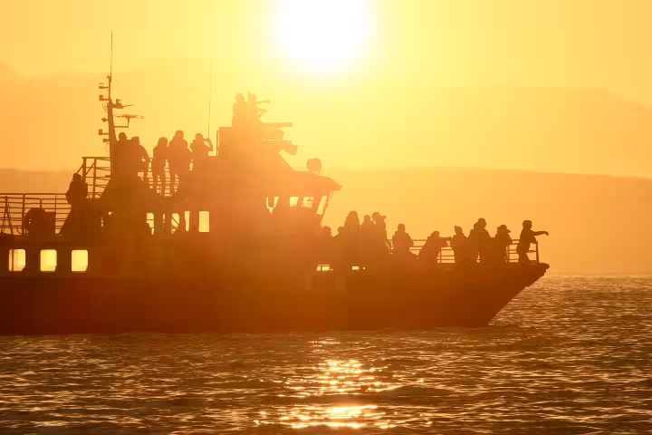 Silhouette of passengers on a whale watching boat sailing at midnight sun in Akureyri, Iceland